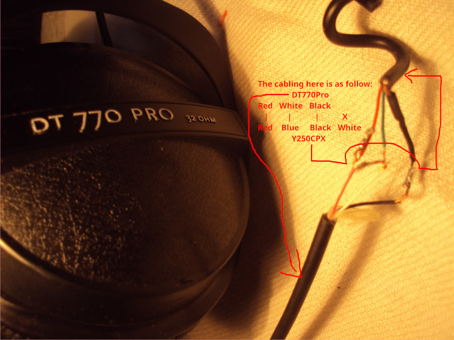 Picture displaying the wires of a BeyerDynamics DT770 Pro headphone cable on the left, soldered to the wires of a Thrustmaster Y250CPX headphone cable on the right.